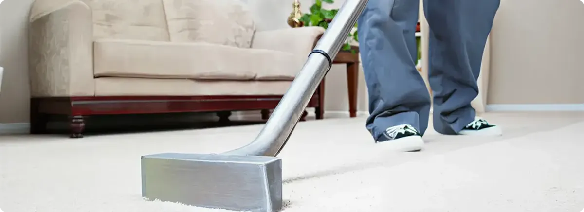 Carpet cleaning technician using a hot-water extraction wand on a light-colored carpet in a living room, Cedar Rapids, IA.