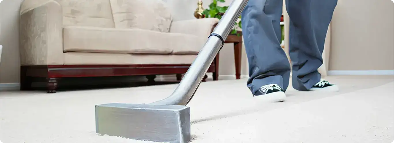 Carpet cleaning technician using a hot-water extraction wand on a light-colored carpet in a living room, Cedar Rapids, IA.
